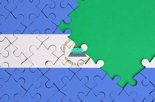 Die Nicaragua-Flagge ist auf einem fertigen Puzzle mit freiem Platz für grüne Kopien auf der rechten Seite abgebildet foto