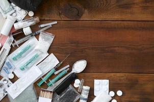 Auf einem alten Holztisch liegen viele Betäubungsmittel und Geräte zur Herstellung von Drogen foto