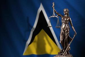 St. Lucia-Flagge mit Statue der Justitia und Gerichtswaage im dunklen Raum. Konzept von Urteil und Bestrafung foto