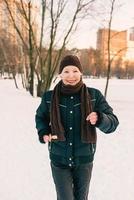 Seniorin mit Hut und sportlicher Jacke, die im Schneewinterpark joggt und Sportübungen macht. winter, alter, sport, aktivität, saisonkonzept foto