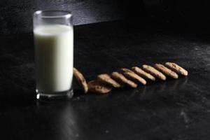 Kekse und Milch auf schwarzem Hintergrund. Platz für Text foto