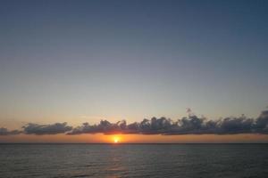 Sonnenscheibe, die über dem Horizont des Meeres aufgeht, Sonnenaufgang, Morgendämmerung foto