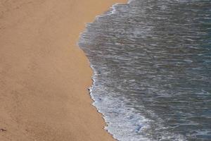 Schaum von den Wellen, wenn sie den Sand am Strand erreichen foto