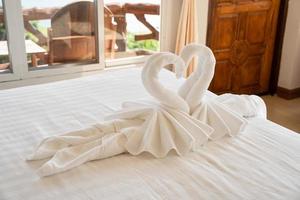 gefaltetes Schwanenhandtuch auf dem Bett im Hotel foto