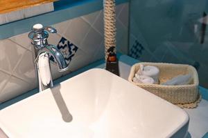 Retro-Waschbecken mit rostfreiem Wasserhahn und Reinigungsgeräten im Badezimmer foto