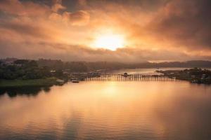 goldener sonnenaufgang über der mon-holzbrücke am songkalia-fluss und dem mon-dorf in sangkhlaburi foto