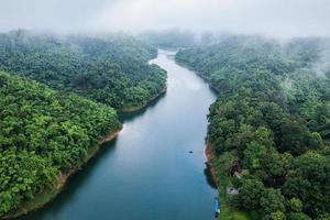 üppiger tropischer Regenwald mit Nebel und Fluss, der morgens im Nationalpark durchfließt foto