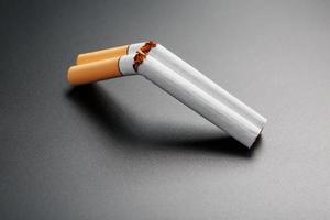 Zwei Zigaretten in Form einer doppelläufigen Schrotflinte auf schwarzem Hintergrund mit Kopierraum. aufhören zu rauchen. das Konzept des Rauchens tötet. foto