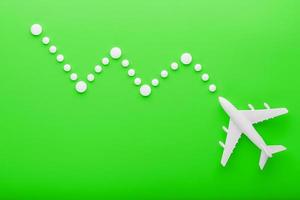 Weißes Passagierflugzeug mit Flugbahnpunkten wie auf einer Streckenkarte, isoliert mit hellgrünem Hintergrund. foto
