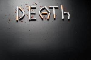 die Inschrift Tod durch Zigaretten auf schwarzem Hintergrund. aufhören zu rauchen. das Konzept des Rauchens tötet. Motivationsaufschrift, mit dem Rauchen aufzuhören, ungesunde Angewohnheit. foto