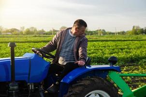 Ein Bauer fährt einen Traktor, während er Kartoffeln erntet. erste Kartoffelernte im zeitigen Frühjahr. Agroindustrie und Agribusiness. Erntemechanisierung in Entwicklungsländern. Landwirtschaft und Ackerland. foto