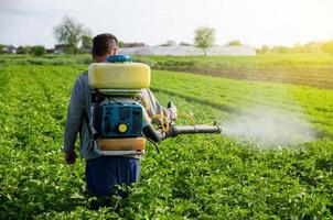 Ein Bauer mit einem Nebelnebelsprühgerät sprüht Fungizide und Pestizide auf Kartoffelbüsche. wirksamer Pflanzenschutz, Auswirkungen auf die Umwelt. Schutz von Kulturpflanzen vor Insekten- und Pilzinfektionen foto
