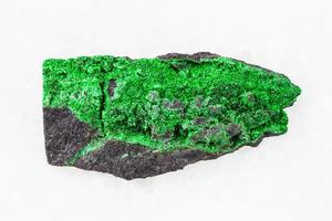 grüne uvarovitkristalle auf rohem felsen auf weiß foto