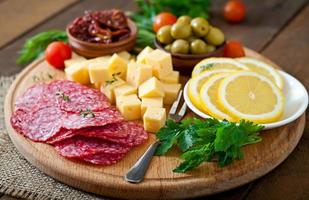 Antipasti-Catering-Platte mit Salami und Käse auf Holzhintergrund foto