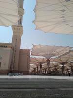 medina, saudi-arabien, 2022 - regenschirmkonstruktion auf dem platz von al-masjid an-nabawi oder der propheten-muhammed-moschee schützen die menschen tagsüber vor der sonne und arbeiten nachts als lichter foto