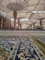 medina, saudi-arabien, 2022 - regenschirmkonstruktion auf dem platz von al-masjid an-nabawi oder der propheten-muhammed-moschee schützen die menschen tagsüber vor der sonne und arbeiten nachts als lichter foto