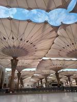 medina, saudi-arabien, 2022 - regenschirmkonstruktion auf dem platz von al-masjid an-nabawi oder der propheten-muhammed-moschee schützen die menschen tagsüber vor der sonne und arbeiten nachts als lichter foto