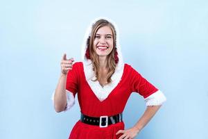 nahaufnahme der kaukasischen glücklichen frau, die weihnachtsmannkleidung trägt, die auf die kamera zeigt foto