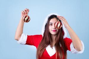 nahaufnahme der kaukasischen glücklichen frau, die weihnachtsmannkleidung trägt, die weihnachtsdekorationen hält foto