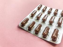 medizinisch-pharmazeutische braune medikamente zur behandlung von krankheiten und zur abtötung von mikroben und viren tabletten und vitaminblasen blasen von coronavirus covid-19 auf rosa hintergrund foto