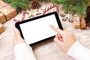Tablet-Computer in Mädchenhänden. tablet-computer mit roter geschenkbox, weihnachtssüßigkeiten und tannenzweigen. Freiraum für Text. Ansicht von oben. Platz kopieren. Nahansicht foto