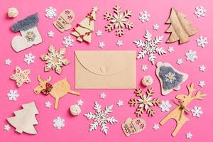 Blick von oben auf den Bastelumschlag auf rosa Hintergrund aus Weihnachtsdekorationen und Spielzeug. Weihnachtsschmuck-Konzept