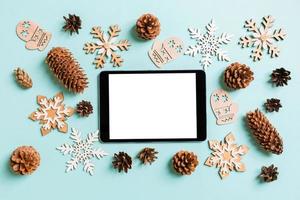 Draufsicht auf digitales Tablet, Urlaubsspielzeug und Dekorationen auf blauem Weihnachtshintergrund. neujahrszeitkonzept foto
