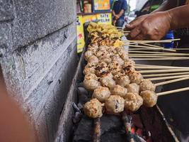 gegrillte Fleischbällchen. traditionelles straßenessen in indonesien, wo der herstellungsprozess auf heißer holzkohle gegrillt wird foto