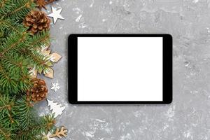 digitales tablet-modell mit rustikalen weihnachtlichen grauen zementhintergrunddekorationen für die app-präsentation. draufsicht mit kopierraum foto