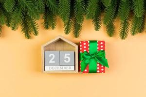 Draufsicht auf Holzkalender, Geschenkbox und Tanne auf buntem Hintergrund. der fünfundzwanzigste dezember. weihnachtszeit mit kopierraum foto