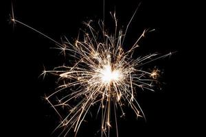 brennende Wunderkerze auf schwarzem Hintergrund isoliert. Thema Feuerwerk. Lichteffekt und Textur. foto