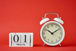 Weißer Retro-Wecker mit Glocken und hölzernen Kalenderblöcken mit Datum 1. März foto