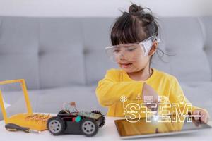 Kleine Mädchen haben Spaß in einer Werkstatt, die Roboterautos kodiert foto