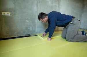 Nahaufnahme des Meisters schneidet die Größe von expandiertem Polystyrol auf dem Boden, den Prozess der Bodenisolierung im Haus. foto