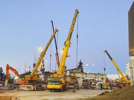 Bau einer kaputten Brücke an einer stark befahrenen Straße. Baumaschinen auf dem Straßenabschnitt errichten eine Überführung, legen eine Asphaltstraße foto