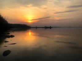 schöner roter sonnenuntergang über dem horizont des wassers im fluss, meer, ozean, see foto