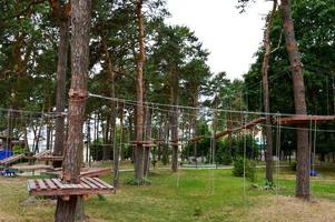 Eine Kletterwand, Trolle und ein Seilpark sorgen für Spiel und Unterhaltung aus Brettern und Bäumen mit Seilen für spielende Kinder und Erwachsene im Wald in der Natur foto