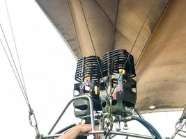 Große, leistungsstarke Metalleisenbrenner, thermische Haartrockner mit einem Feuer zum Erhitzen heißer Luft in einem großen, mehrfarbigen, hellen, runden, regenbogenfarbenen, gestreiften fliegenden Ballon. der Hintergrund foto