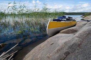 Ein Dreisitzer-Kajak mit Rudern parkt am felsigen Ufer des Sees in einer wunderschönen Landschaft. Aktive Erholung. foto