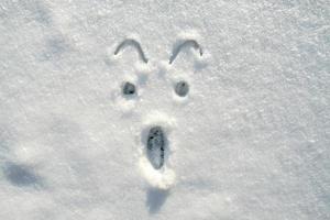 das Gesicht eines verängstigten, schockierten Smileys, der an einem sonnigen Wintertag auf den Schnee gemalt wurde. Platz kopieren. foto