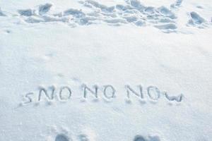 Wort Schnee und dreimal in großen Lettern nein auf eine Schneewehe geschrieben. frühlingserwartungskonzept. Platz kopieren. kreative Idee. foto