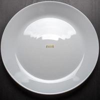 Das Wort Essen besteht aus Nudelbuchstaben auf einem weißen leeren Teller auf einem schwarzen Tisch. foto
