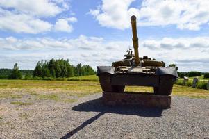 Ein großer, grüner, militärisch gepanzerter, tödlich gefährlicher russischer syrischer Kampfpanzer aus Eisen mit einem Geschützturm und einer Gans ist vor blauem Himmel und Wolken außerhalb der Stadt geparkt foto