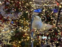 Christbaumschmuck. Spielzeugvogel sitzt auf einem Astbaum in einem Märchenwald auf verschwommenem Weihnachtshintergrund. das konzept von neujahr und weihnachten. festliche Dekoration foto