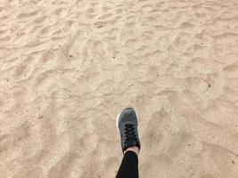 der fuß im grauen stiefelschuh macht einen schritt vor dem hintergrund eines natürlichen losen gelben goldenen schönen warmen strandsandes foto