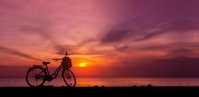 Silhouettenfoto des Fahrradparkplatzes vor dem See im Sonnenuntergang. Dämmerung Himmel und See als Hintergrund. ein kohlenstofffreies Fahrzeug inmitten der Natur. Umweltschutz und nachhaltiger Lebensstil foto