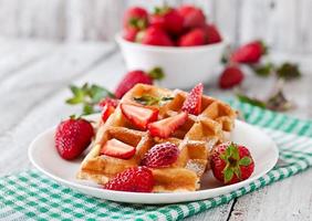 Belgische Waffeln mit Erdbeeren und Minze auf weißem Teller foto