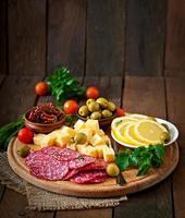 Antipasti-Catering-Platte mit Salami und Käse auf Holzhintergrund foto