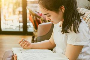 süßes asiatisches junges Mädchen, das Hausaufgaben macht, Papier, warmer Vintage-Farbton foto