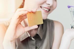 Nahaufnahmemädchen-Teenagerhand unter Verwendung der Kreditkarte mit glücklichem Lächelngefühlskonzept foto